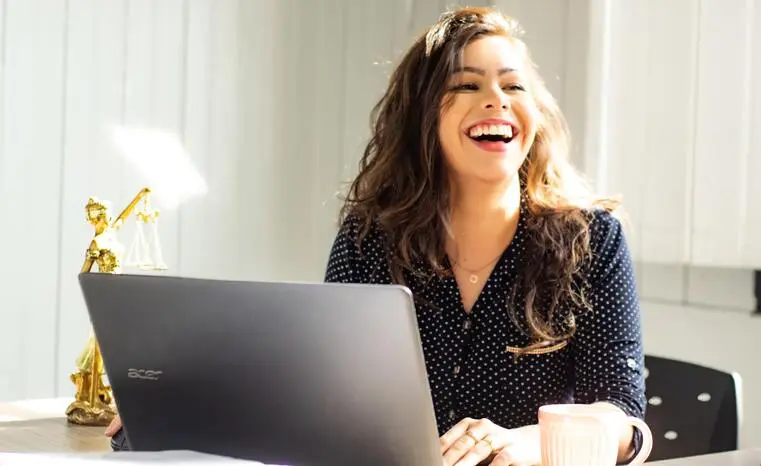 Jeune femme assise à son bureau et éclatant de rire